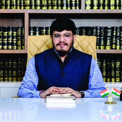 Divy Trivedi, Chair of the Board, seated at a desk in front of law books