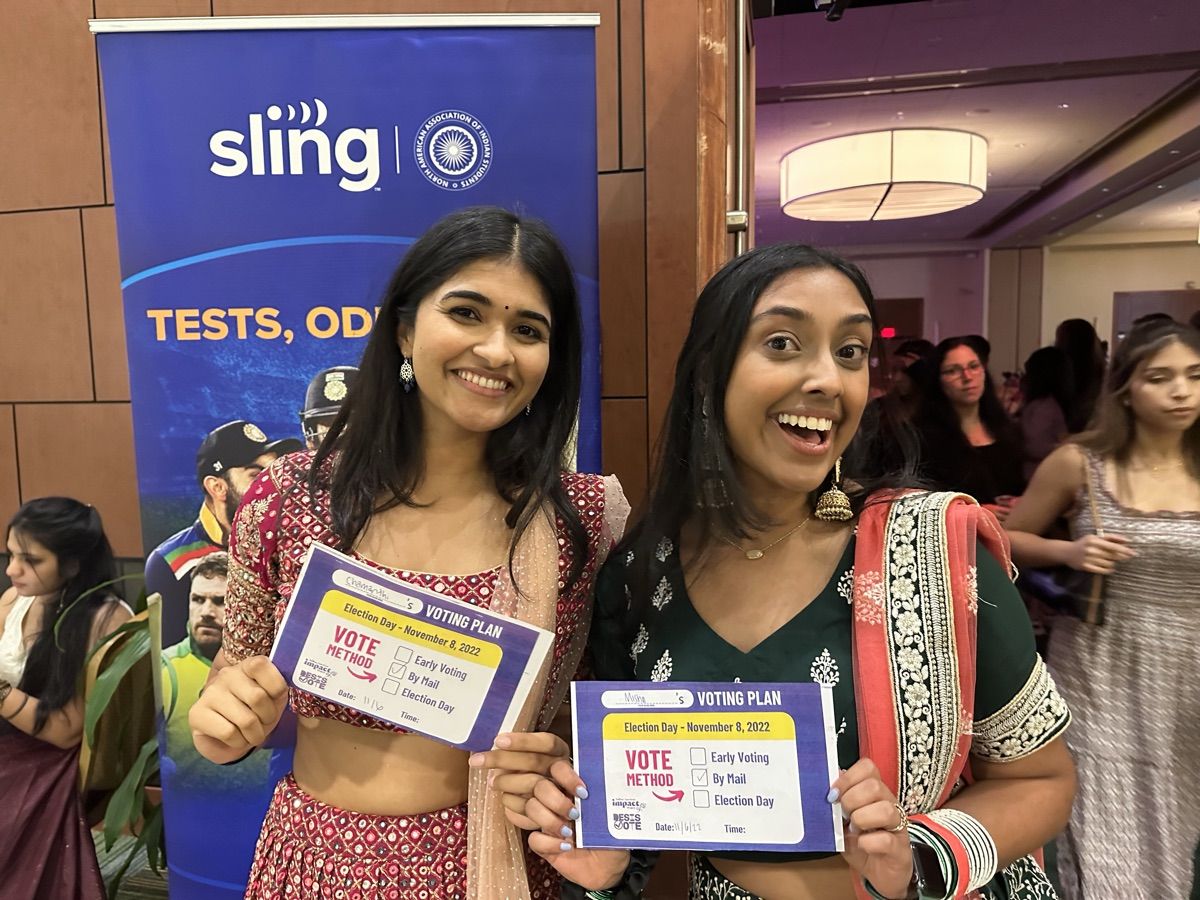 Two students smiling and holding voting plan cards